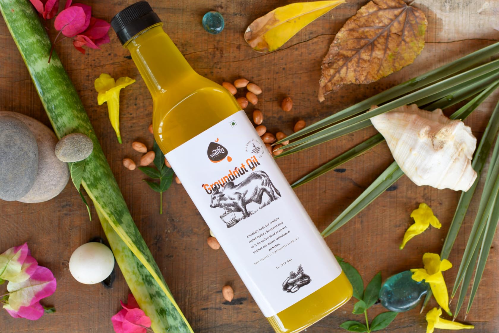 Vedika Organics groundnut oil bottle with fresh peanuts and natural ingredients on wooden background